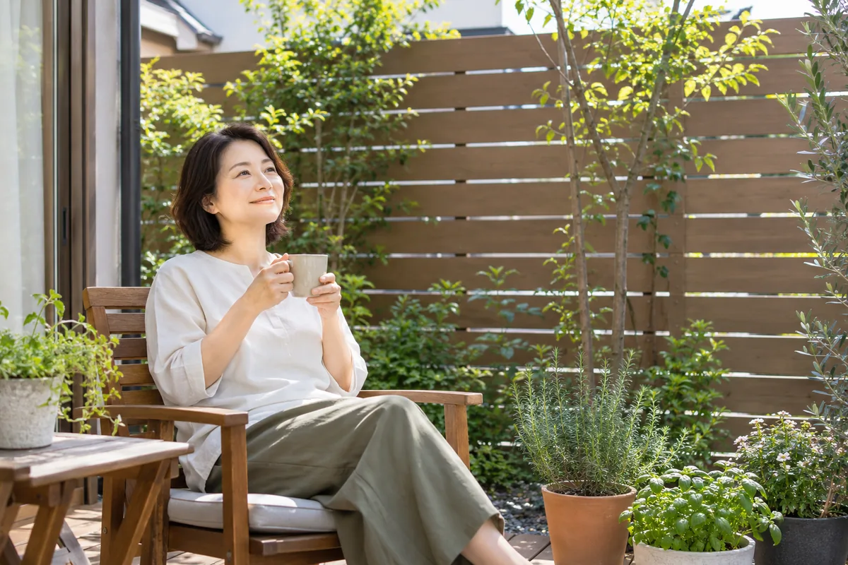 目隠しフェンスに囲まれた庭でくつろぐ女性。交換で決めたい高さと透け具合のイメージ
