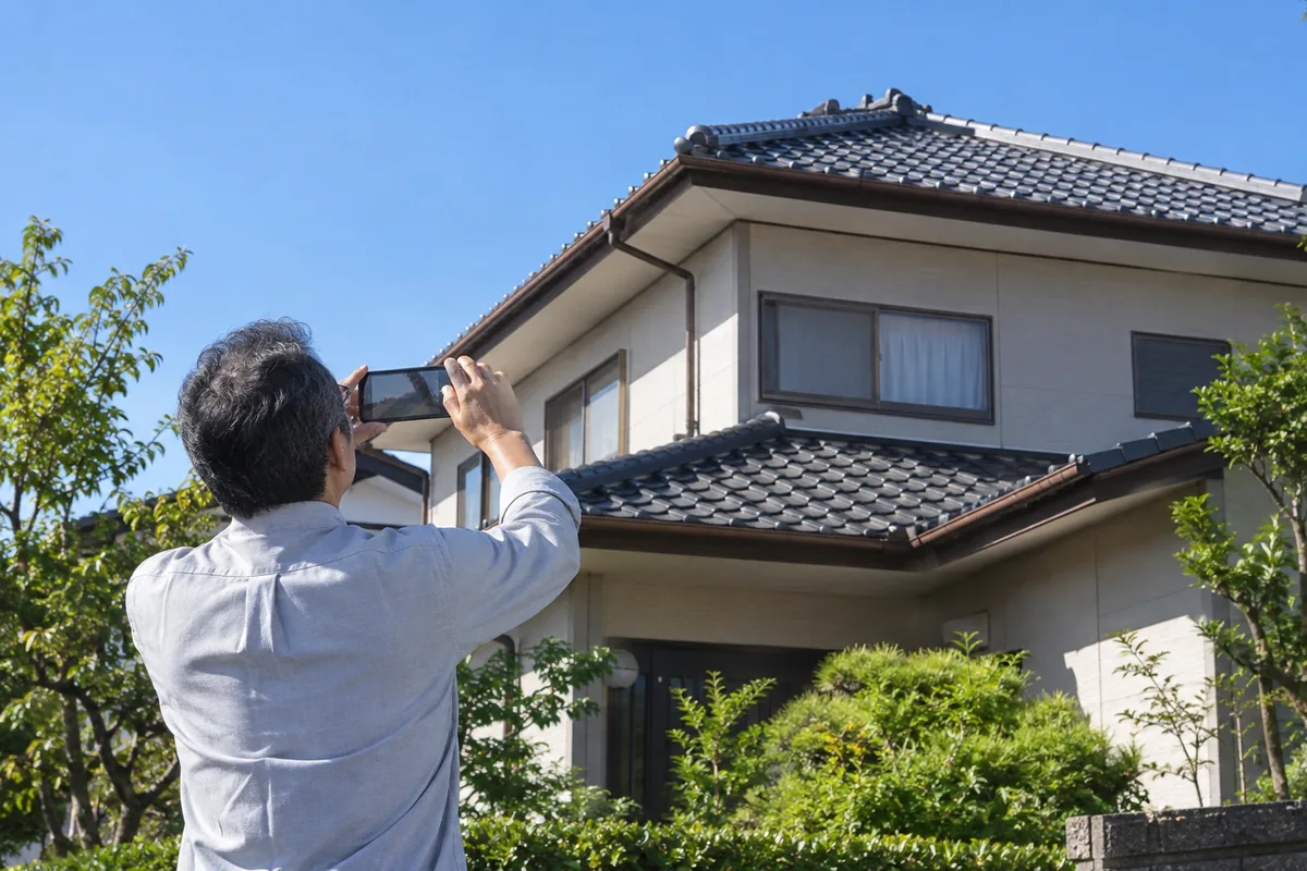 火災保険で屋根の修理を相談する前に、地上から被害を写真に残すイメージ
